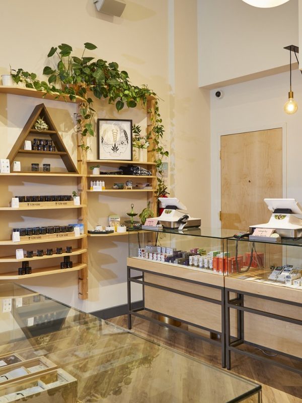 A well-organized retail cannabis dispensary with glass display cases and wooden shelves filled with cannabis products.