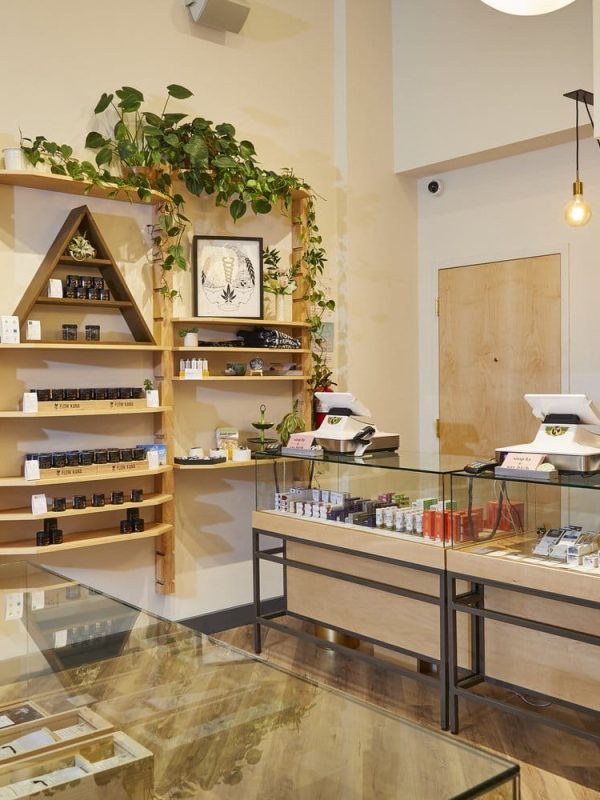 A well-organized retail cannabis dispensary with glass display cases and wooden shelves filled with cannabis products.